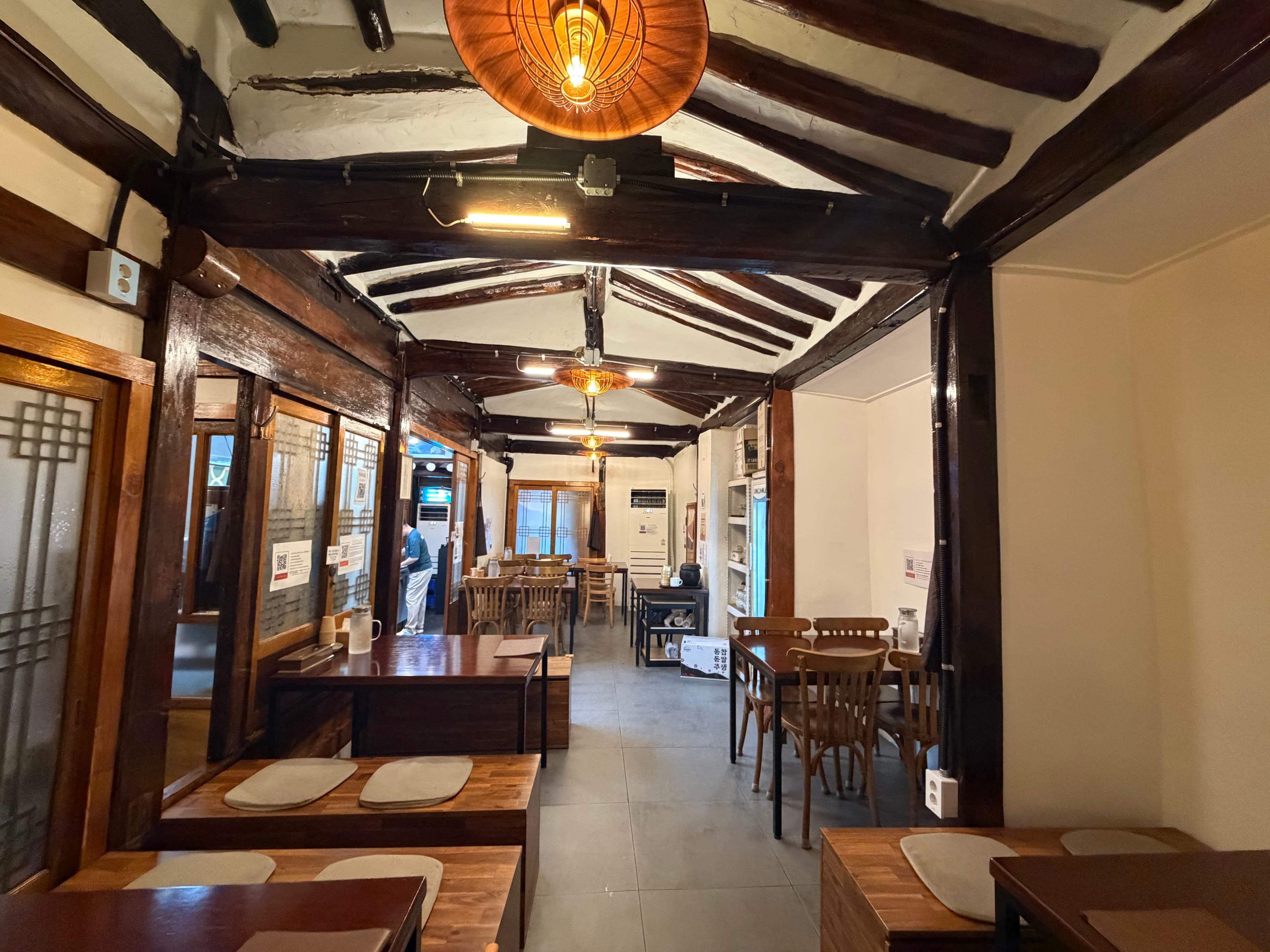 Hanok hall with exposed beams and wooden tables