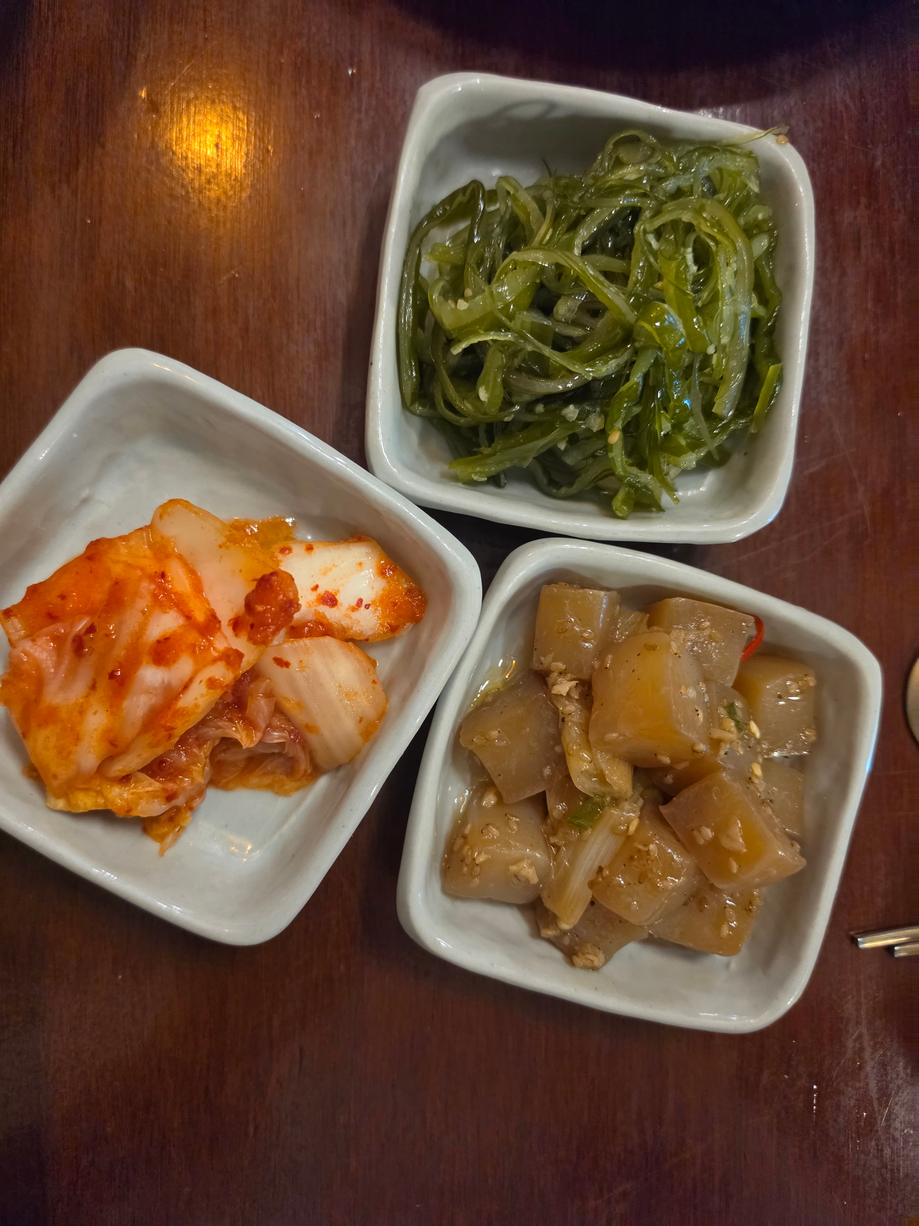 Banchan in square bowls on oak
